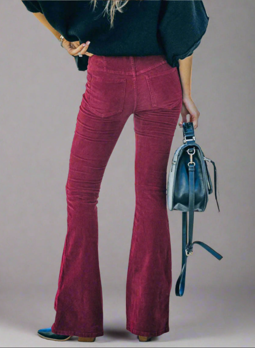 Vrouw in rode flared broek met zwarte tas, buiten op straat. Modieuze outfit, herfstkleding, trendy damesmode.