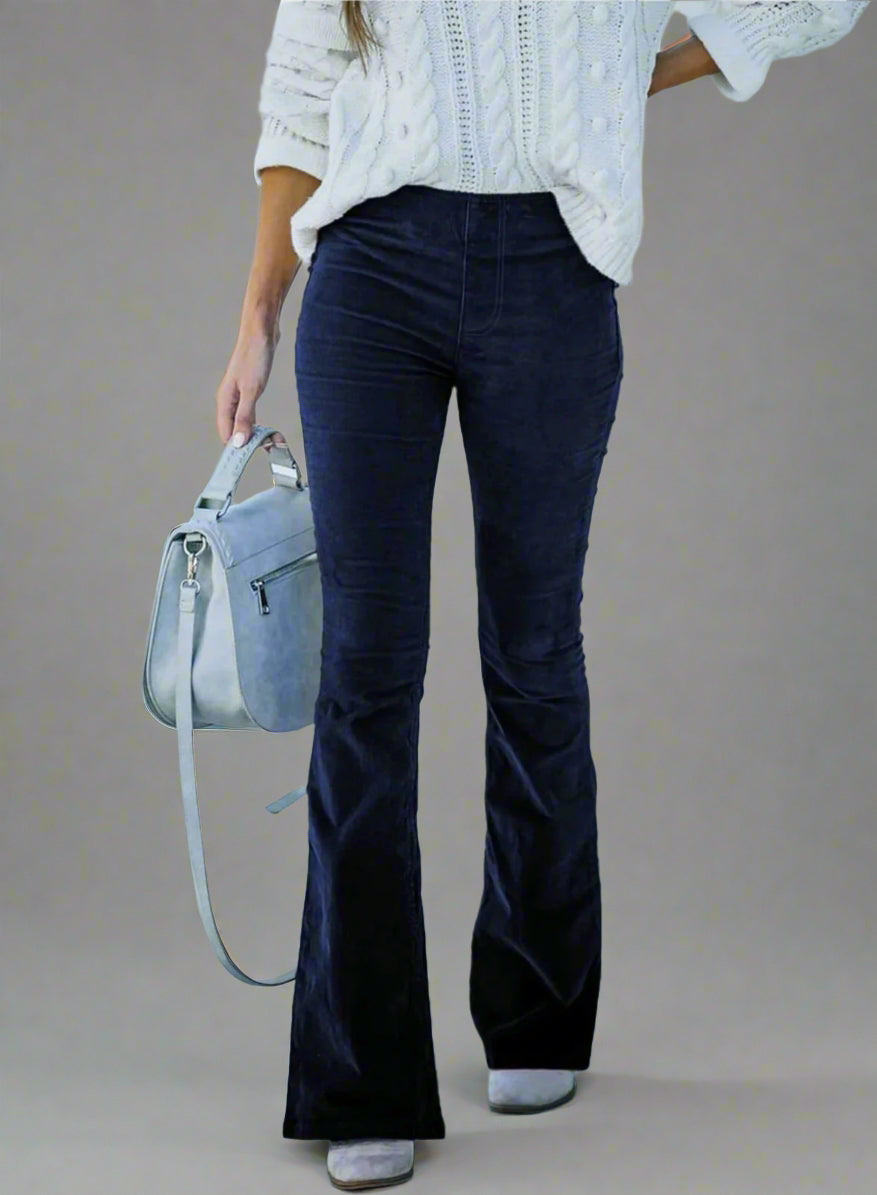 Vrouw draagt zwarte flared broek en witte kabeltrui, met grijze handtas. Modieuze herfstoutfit, casual stijl, trendy dameskleding.