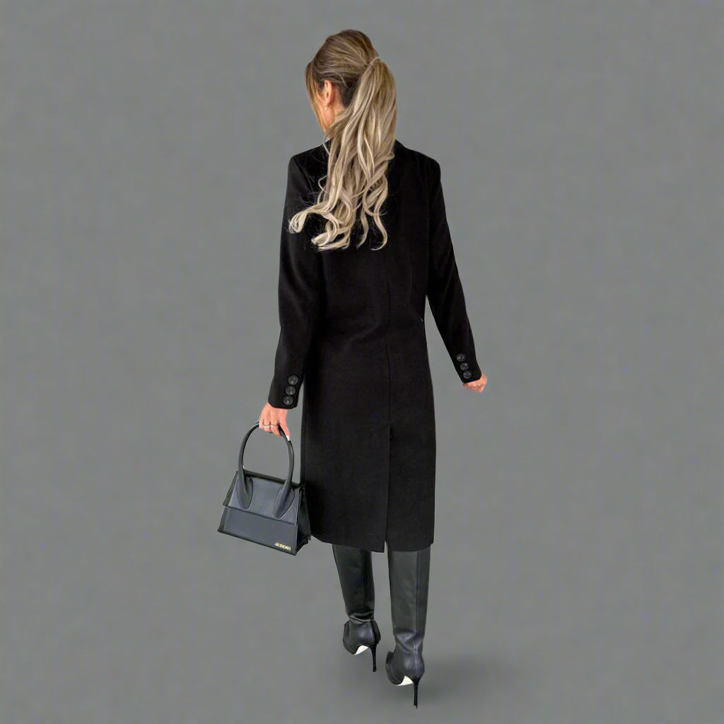 Vrouw in zwarte winterjas, hoge laarzen en met een zwarte handtas. Stijlvolle wintermode, elegante dameskleding, moderne outfit.
