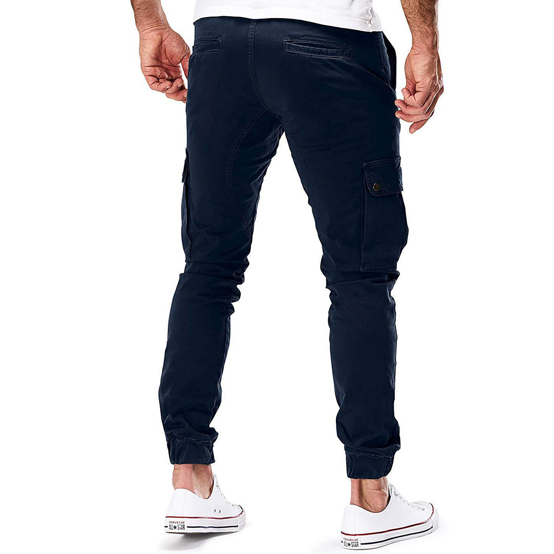 Man in donkerblauwe cargobroek met zakken, casual stijl, gecombineerd met witte sneakers. Ideaal voor herenmode en streetwear trends.