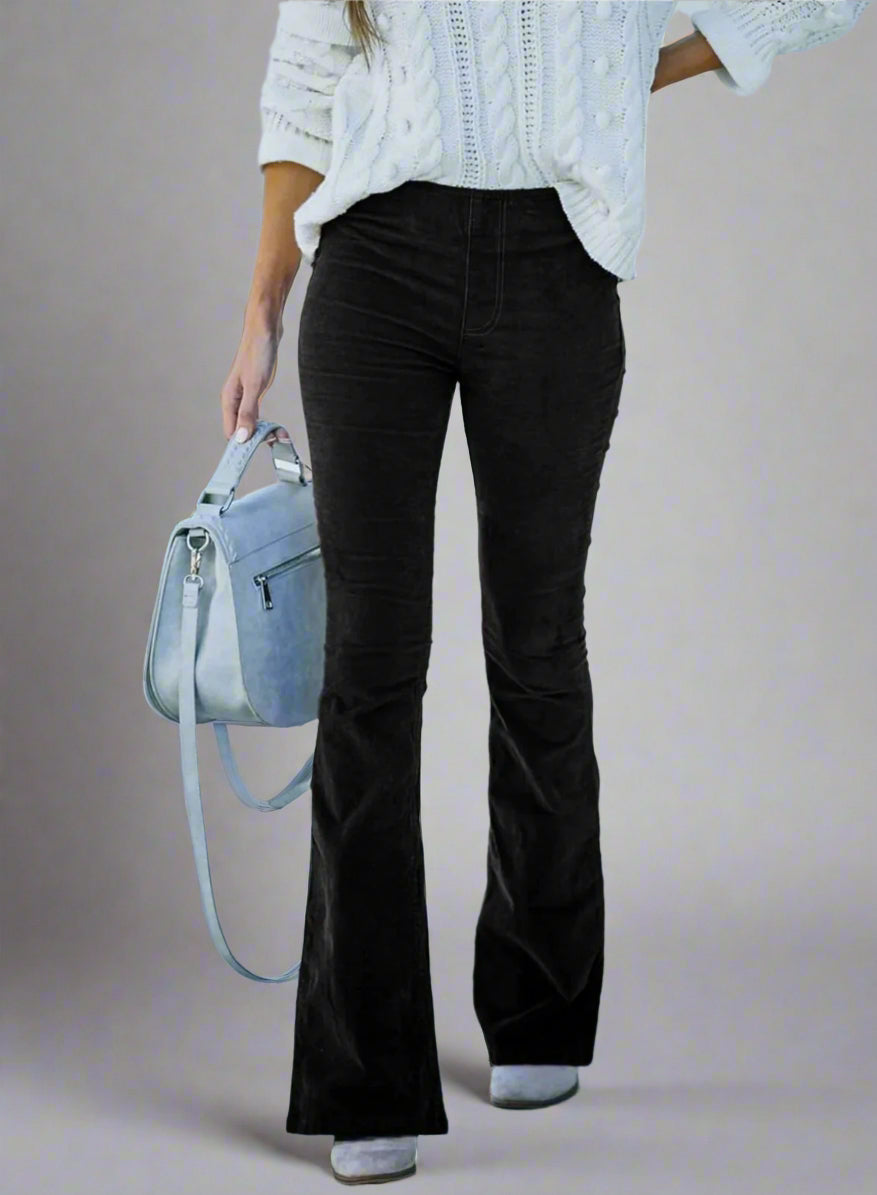 Vrouw in witte kabeltrui met zwarte flared broek en grijze handtas. Modieuze herfstoutfit, casual stijl, straatmode.