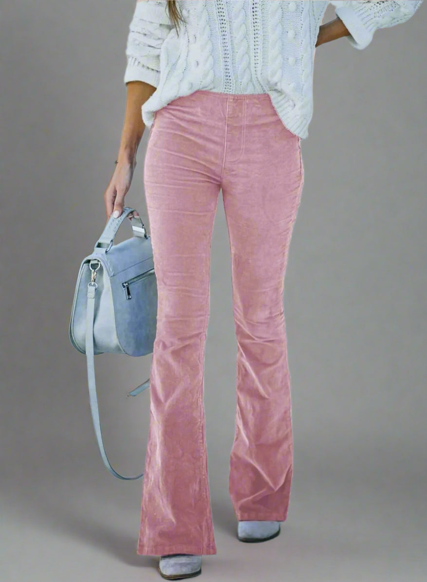 Vrouw draagt roze flared broek en witte trui, met grijze handtas. Modieuze dameskleding, trendy outfit, casual stijl.