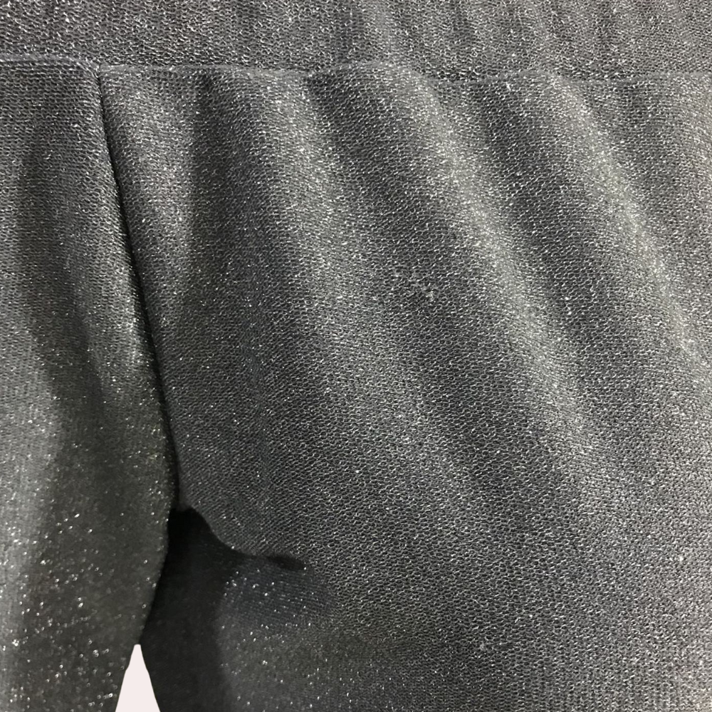 Zwarte glinsterende stof close-up, detail van een Vilja kledingstuk. Luxe textuur, modieuze uitstraling, hoogwaardige materialen.