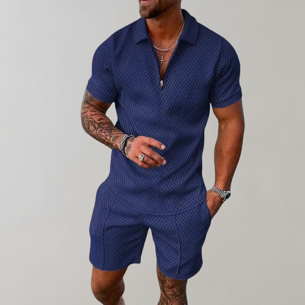 Man in donkerblauw zomerset voor heren met geometrisch patroon, korte mouwen en korte broek. Stijlvolle herenkleding, casual zomeroutfit.